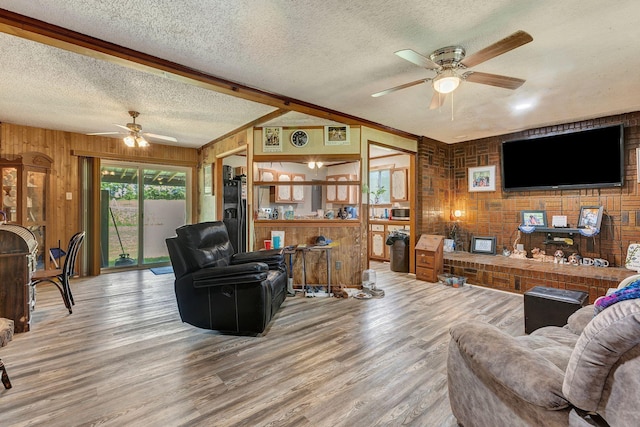 111 School St, Cumberland Furnace, TN 37051 - living area with ceiling fan, a textured ceiling, wooden walls, a brick fireplace, and wood finished floors