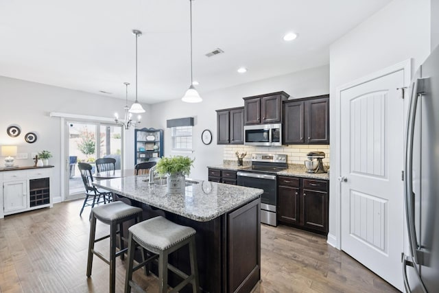 2426 Telford Ln, Murfreesboro, TN 37128 - kitchen with appliances with stainless steel finishes, a kitchen bar, tasteful backsplash, light stone counters, and a kitchen island with sink