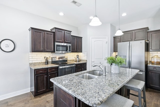 2426 Telford Ln, Murfreesboro, TN 37128 - kitchen featuring stainless steel appliances, a breakfast bar, dark brown cabinets, decorative backsplash, and dark wood-type flooring