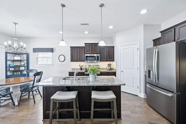 2426 Telford Ln, Murfreesboro, TN 37128 - kitchen featuring appliances with stainless steel finishes, a chandelier, dark brown cabinets, decorative backsplash, and light stone countertops