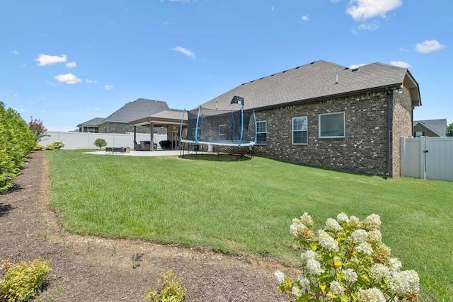 2426 Telford Ln, Murfreesboro, TN 37128 - rear view of house with a trampoline, a patio, a fenced backyard, brick siding, and a shingled roof