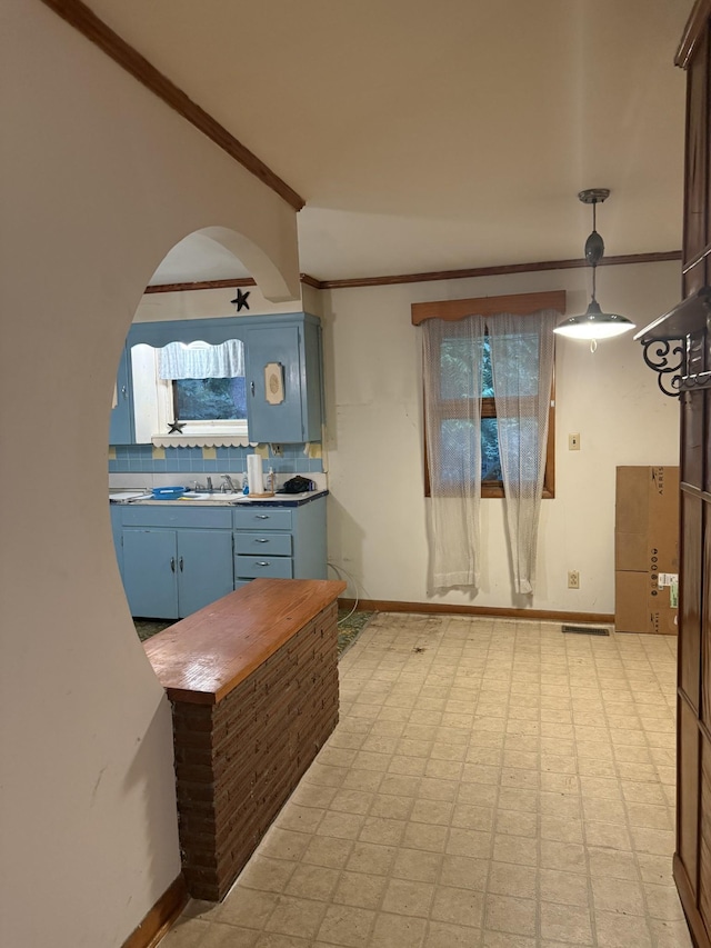 887 Elwood Dr, Clarksville, TN 37040 - kitchen featuring blue cabinetry, light floors, ornamental molding, tasteful backsplash, and arched walkways
