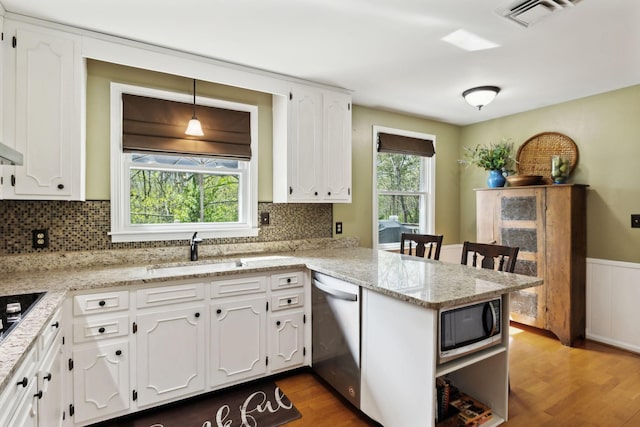 6002 Temple Rd, Nashville, TN 37221 - kitchen featuring appliances with stainless steel finishes, a peninsula, white cabinets, wood finished floors, and backsplash