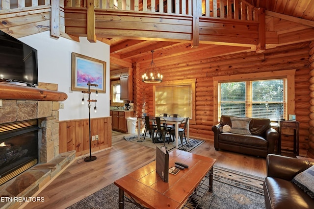 849 Golf View Blvd, Pigeon Forge, TN 37863 - living room featuring a wainscoted wall, beam ceiling, a chandelier, a stone fireplace, and light wood-style flooring
