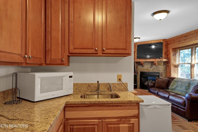 849 Golf View Blvd, Pigeon Forge, TN 37863 - kitchen with white microwave, open floor plan, a stone fireplace, light stone counters, and wood finished floors