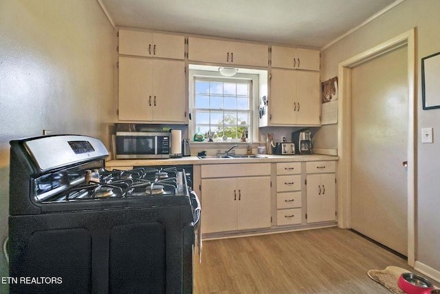 110 Clark Ave, Jamestown, TN 38556 - kitchen featuring black range with gas stovetop, stainless steel microwave, light wood finished floors, light countertops, and crown molding
