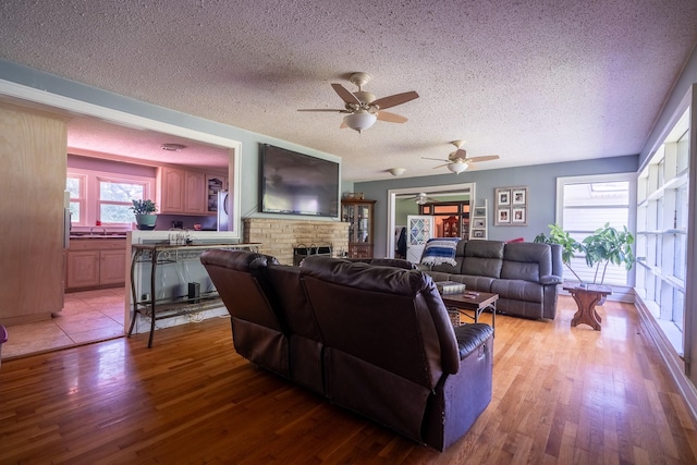 1539 Old Florence Rd, Lawrenceburg, TN 38464 - living room featuring a textured ceiling, ceiling fan, light wood-type flooring, and a fireplace
