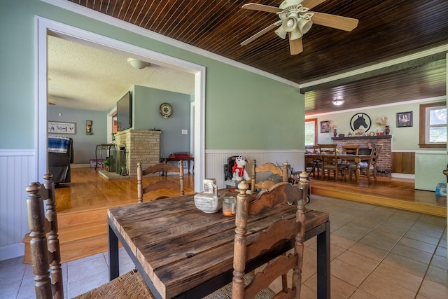 1539 Old Florence Rd, Lawrenceburg, TN 38464 - dining room with wainscoting, a brick fireplace, tile patterned floors, ceiling fan, and ornamental molding