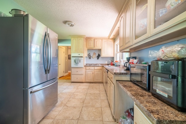 1539 Old Florence Rd, Lawrenceburg, TN 38464 - kitchen with stainless steel appliances, light brown cabinets, a textured ceiling, glass insert cabinets, and light tile patterned floors