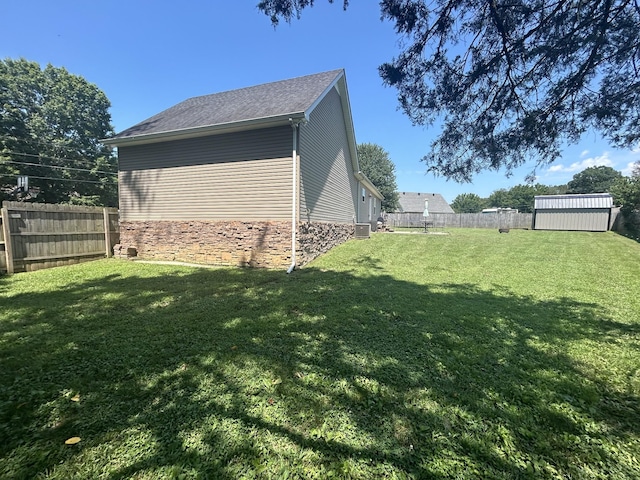 49 Rebecca Ln W, Estill Springs, TN 37330 - view of side of property with a fenced backyard, stone siding, a storage shed, and roof with shingles