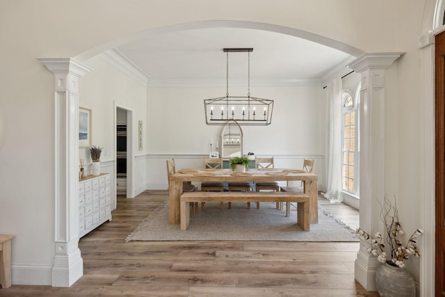 8217 W Chase Ct, Nashville, TN 37221 - dining room with arched walkways, decorative columns, light wood-style floors, ornamental molding, and a wainscoted wall