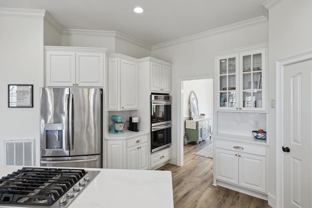8217 W Chase Ct, Nashville, TN 37221 - kitchen featuring stainless steel appliances, white cabinets, glass insert cabinets, ornamental molding, and wood finished floors