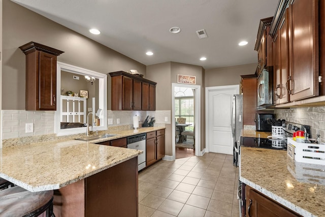 1192 Wicke Rd, Adams, TN 37010 - kitchen featuring stainless steel appliances, decorative backsplash, a peninsula, light tile patterned floors, and a kitchen breakfast bar