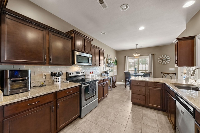 1192 Wicke Rd, Adams, TN 37010 - kitchen featuring appliances with stainless steel finishes, decorative backsplash, dark brown cabinetry, recessed lighting, and light stone countertops