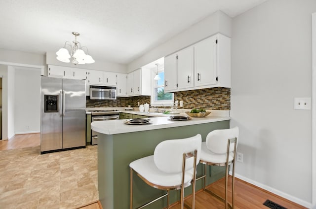 215 Patrick St, Estill Springs, TN 37330 - kitchen featuring stainless steel appliances, decorative backsplash, a chandelier, a peninsula, and light countertops
