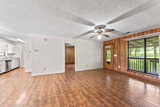 2200 Rawls Rd, Greenbrier, TN 37073 - unfurnished living room with wood finished floors, ceiling fan, wood walls, and a textured ceiling