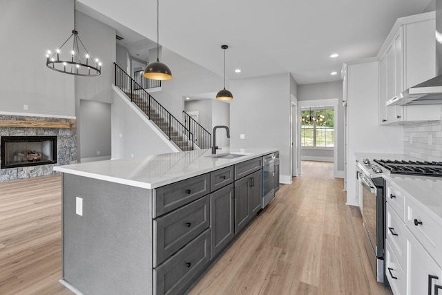 6021 Riverview Dr, Pegram, TN 37143 - kitchen with appliances with stainless steel finishes, wall chimney range hood, white cabinets, light wood finished floors, and gray cabinetry