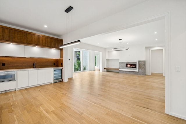 4045 Outer Dr, Nashville, TN 37204 - kitchen with beverage cooler, white cabinetry, light wood-style floors, a high end fireplace, and recessed lighting