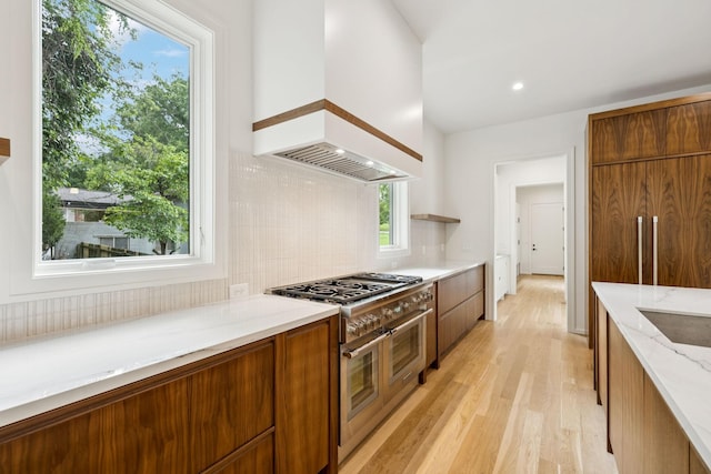 4045 Outer Dr, Nashville, TN 37204 - kitchen featuring range with two ovens, custom range hood, light wood finished floors, brown cabinetry, and modern cabinets