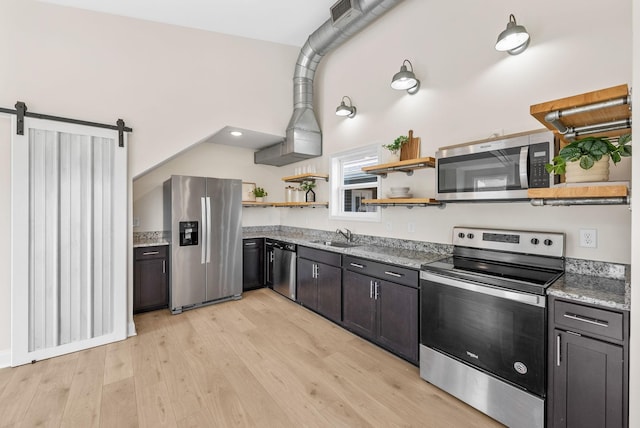 76 W High St, Clarksville, TN 37040 - kitchen featuring stainless steel appliances, open shelves, light wood-style flooring, light stone counters, and a barn door