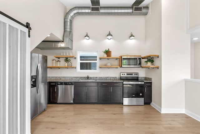 76 W High St, Clarksville, TN 37040 - kitchen with stainless steel appliances, open shelves, stone counters, light wood finished floors, and a barn door