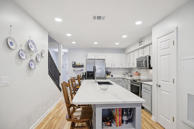 4858 Chelanie Cir, Murfreesboro, TN 37129 - kitchen with stainless steel appliances, light wood-style floors, a breakfast bar area, a center island with sink, and backsplash