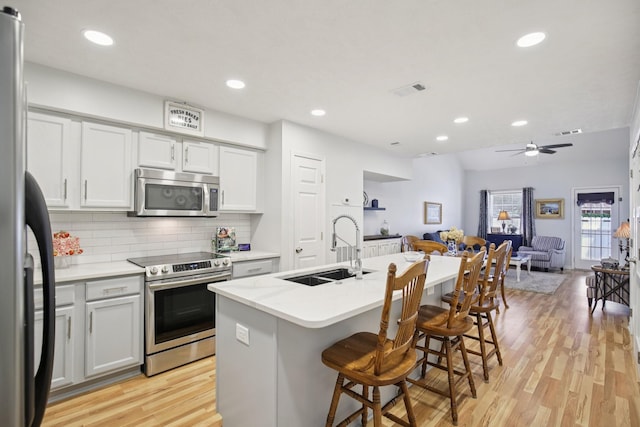4858 Chelanie Cir, Murfreesboro, TN 37129 - kitchen featuring stainless steel appliances, open floor plan, light wood-type flooring, decorative backsplash, and light countertops