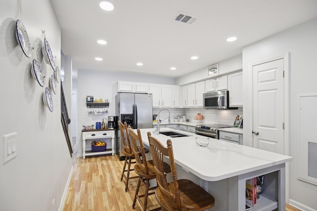 4858 Chelanie Cir, Murfreesboro, TN 37129 - kitchen with appliances with stainless steel finishes, light wood-style flooring, tasteful backsplash, recessed lighting, and a breakfast bar area