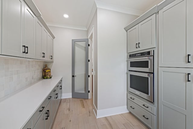 9409 Clovercroft Rd, Franklin, TN 37067 - kitchen featuring stainless steel double oven, tasteful backsplash, light wood-type flooring, light countertops, and crown molding