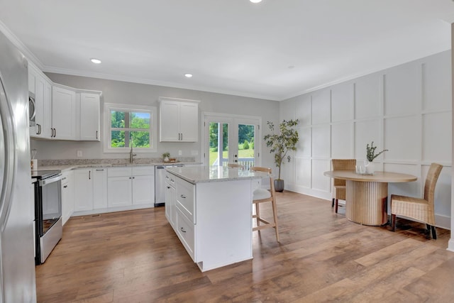 1268 S Tidwell Rd, Bon Aqua, TN 37025 - kitchen with stainless steel appliances, ornamental molding, a decorative wall, a breakfast bar, and white cabinets