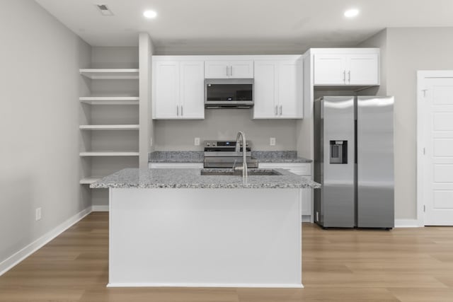 415 9th St, Clarksville, TN 37040 - kitchen with appliances with stainless steel finishes, white cabinetry, a kitchen island with sink, light wood finished floors, and open shelves