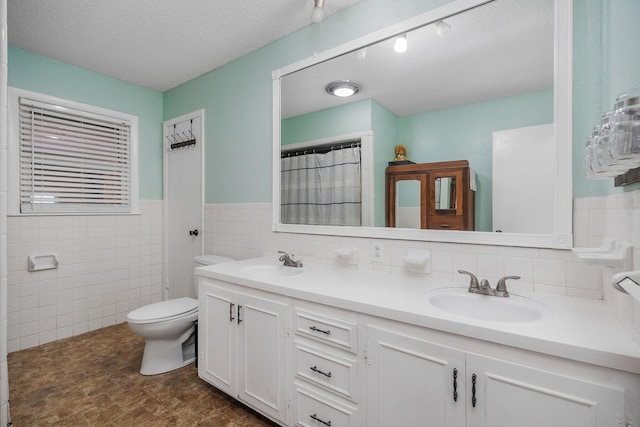 6191 Baxter Rd, Baxter, TN 38544 - bathroom featuring double vanity, tile walls, a textured ceiling, and wainscoting