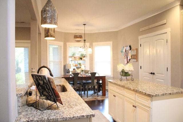 8009 Shelly Plum Dr, Murfreesboro, TN 37128 - kitchen featuring a center island, light stone counters, hanging light fixtures, wood finished floors, and crown molding