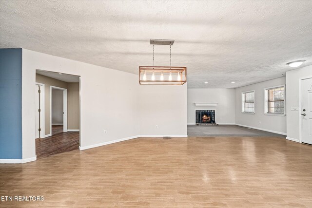 708 Poston Dr, Monterey, TN 38574 - unfurnished living room with wood finished floors, a textured ceiling, and a lit fireplace