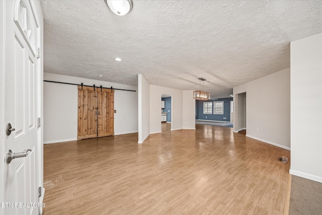 708 Poston Dr, Monterey, TN 38574 - unfurnished living room featuring light wood-type flooring, a barn door, a textured ceiling, and a chandelier