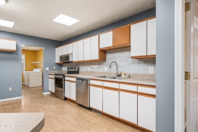 708 Poston Dr, Monterey, TN 38574 - kitchen featuring stainless steel appliances, washer and dryer, light countertops, white cabinets, and backsplash