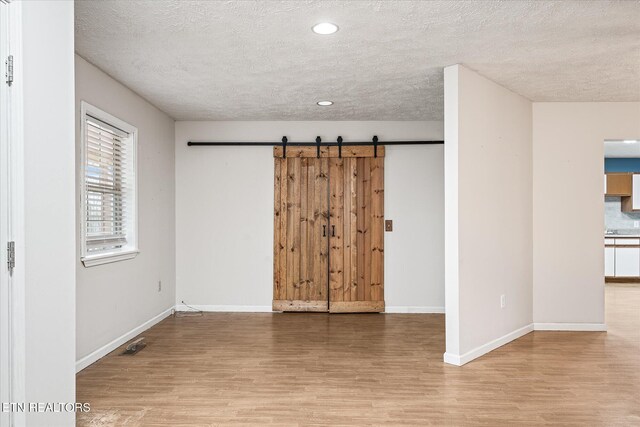 708 Poston Dr, Monterey, TN 38574 - empty room with wood finished floors, a textured ceiling, recessed lighting, and a barn door