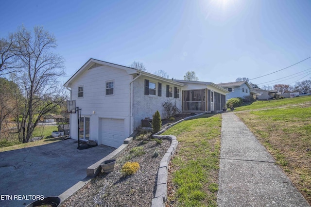 8114 Sharp Rd, Powell, TN 37849 - ranch-style home featuring a sunroom, asphalt driveway, an attached garage, brick siding, and a front lawn