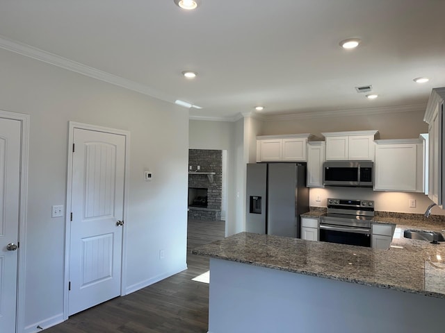 9021 Ada Way, Fairview, TN 37062 - kitchen with stainless steel appliances, dark stone countertops, dark wood-type flooring, white cabinets, and ornamental molding