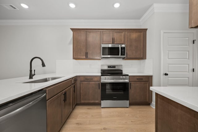 522 Rohan Dr, Murfreesboro, TN 37129 - kitchen featuring appliances with stainless steel finishes, crown molding, light countertops, light wood-style flooring, and decorative backsplash