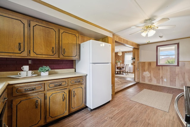 2274 Indian Mound Rd, Woodlawn, TN 37191 - kitchen featuring freestanding refrigerator, stove, brown cabinets, a ceiling fan, and wooden walls