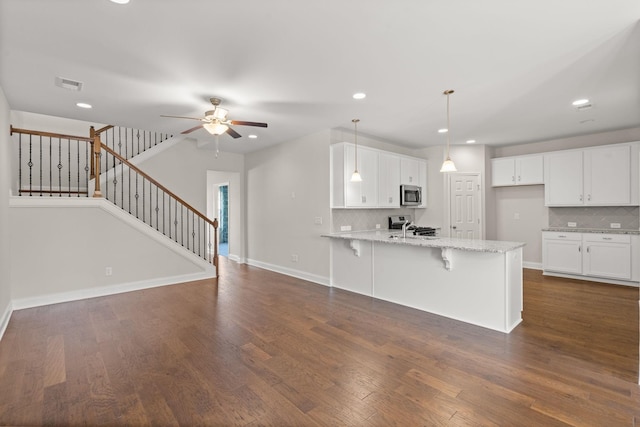 604 Douglas St, Lebanon, TN 37087 - kitchen featuring stainless steel microwave, a peninsula, a ceiling fan, tasteful backsplash, and white cabinetry