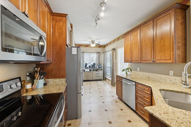 131 E Robertson Rd, Castalian Springs, TN 37031 - kitchen with stainless steel appliances, brown cabinets, light stone countertops, a ceiling fan, and a textured ceiling