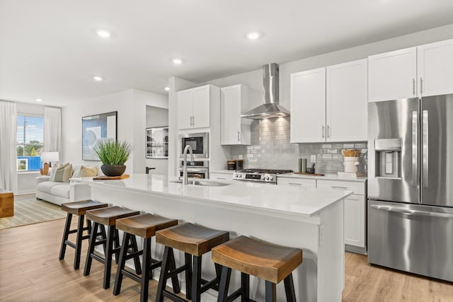 3412 Shigo St, Murfreesboro, TN 37130 - kitchen with stainless steel appliances, wall chimney range hood, light wood finished floors, light countertops, and a center island with sink