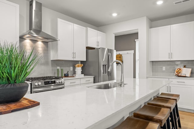 3412 Shigo St, Murfreesboro, TN 37130 - kitchen featuring wall chimney range hood, appliances with stainless steel finishes, light stone counters, tasteful backsplash, and white cabinetry