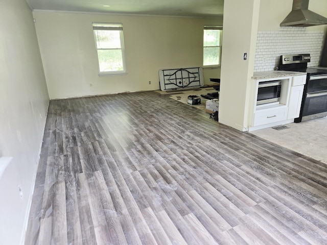 213 April Dr, Old Hickory, TN 37138 - kitchen with wall chimney range hood, stainless steel appliances, light wood-style flooring, white cabinetry, and ornamental molding