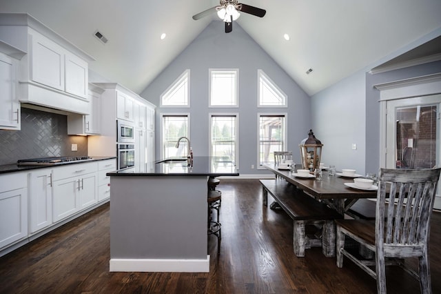 2331 Lionheart Dr, Murfreesboro, TN 37130 - kitchen featuring dark countertops, stainless steel appliances, a ceiling fan, a center island with sink, and white cabinetry