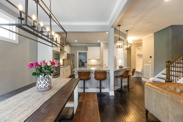 7156 Triple Crown Ln, Fairview, TN 37062 - kitchen featuring stainless steel appliances, dark wood finished floors, crown molding, a breakfast bar area, and backsplash
