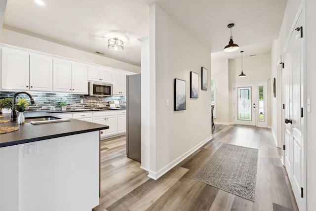 2414 Keegan Dr, Murfreesboro, TN 37130 - kitchen with dark countertops, stainless steel appliances, tasteful backsplash, white cabinetry, and light wood-style flooring