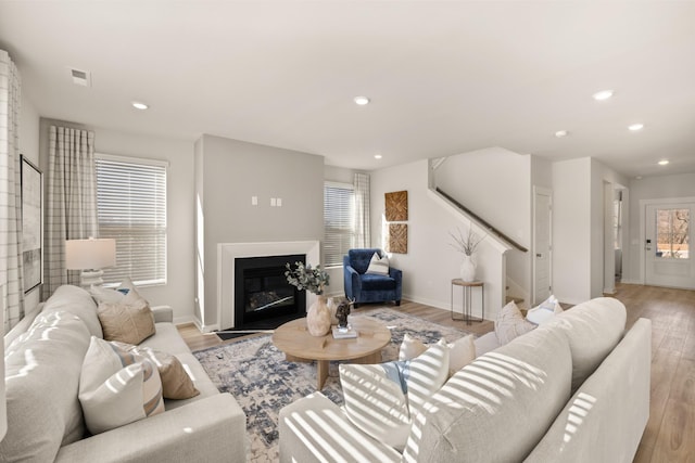 1243 Tucker Dr, Lebanon, TN 37087 - living room with healthy amount of natural light, light wood finished floors, recessed lighting, a glass covered fireplace, and stairs